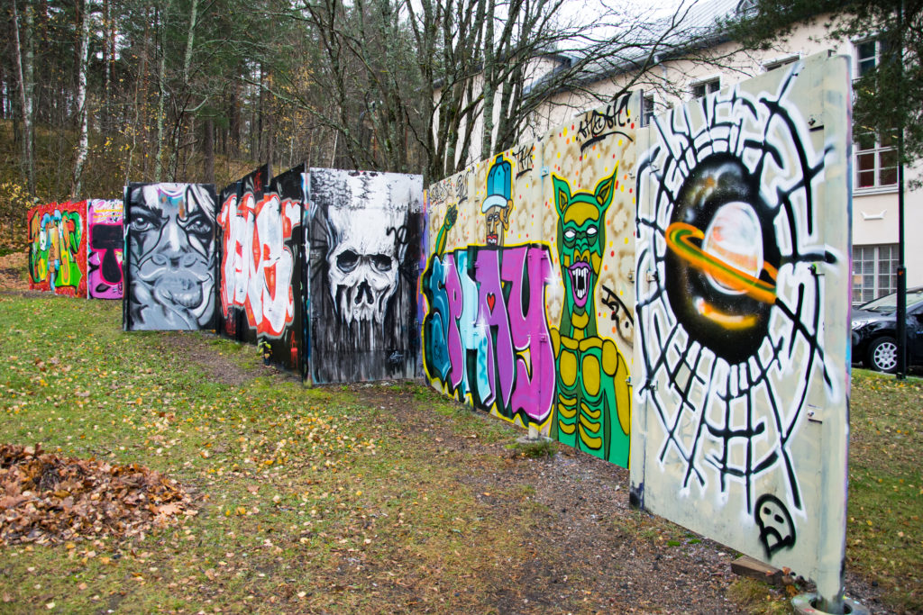 Harjulan graffitiseinä koostuu levyistä ja nousee loivaa rinnettä.