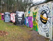 Harjulan graffitiseinä koostuu levyistä ja nousee loivaa rinnettä.
